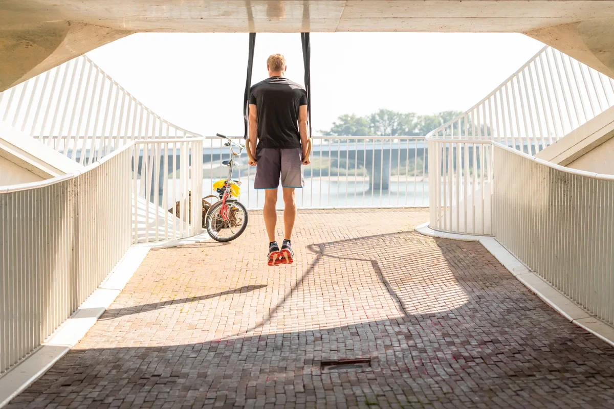 Sporter traint met trainingsbanden onder een brug aan de rivier in Nijmegen